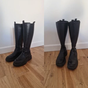Svarta höga stövlar - Snygga svarta höga stövlar i skinn med en robust sula. Perfekta för både stil och komfort under kyligare dagar. De har en klassisk design som passar till många olika outfits.