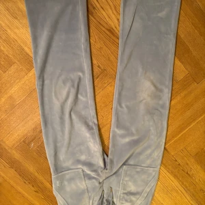 Ljusblå mjukisbyxor från Juicy Couture - Snygga ljusblåa mjukisbyxor från Juicy Couture med broderad logga på framsidan. Byxorna har en bekväm passform och är perfekta för en avslappnad stil. De har även fickor baktill med knappar för extra detaljer.