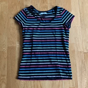 svart t-shirt med färgglada ränder - svart t-shirt med färgglada ränder i vit, rosa, grön, och blå.