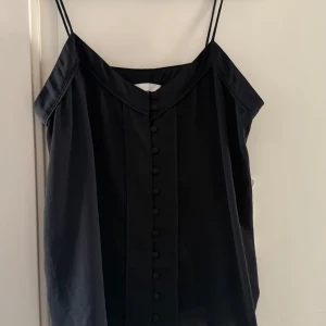 Svart ärmlös topp från H&M Conscious - Snygg svart ärmlös topp från H&M Conscious med knappar framtill. 