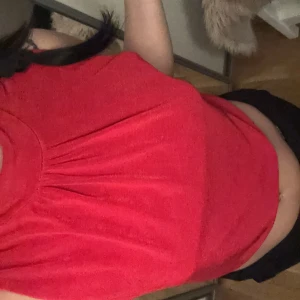 Röd ärmlös topp - Säljer en snygg röd ärmlös topp med öppen rygg. Perfekt för varma dagar eller en utekväll. Toppen har en enkel och stilren design som gör den lätt att matcha med olika outfits.