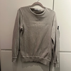 Grå tröja från Stone Island - Säljer en stilren grå tröja från Stone Island med broderad logga på bröstet. Som är i bra skick