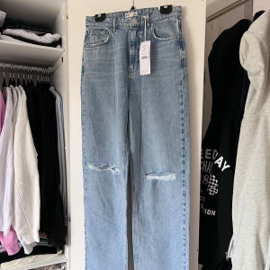 Ljusblå jeans med slitningar (NYA) - Snygga ljusblå jeans från Gina Tricot med slitningar på knäna. De har en klassisk femficksdesign och en knappgylf. Perfekta för en avslappnad stil. Storleken är 36 och de är baggy på mig som normalt har 36 i jeans - alltså oversized. Nya med prislapp kvar på 🩵 Önskar du veta exakta mått? Tveka inte att höra av dig!