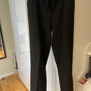 Kostymbyxor  - Svarta, raka, högmidjade kostymbyxor från NAKD. Men en fejk bakficka. Varan är som ny, men ej med lapp kvar. 