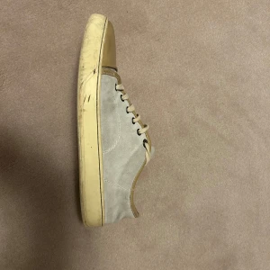 Beige sneakers från Lanvin - Snygga beige sneakers från Lanvin med snörning och en kontrasterande tå i ljusbrun färg. Skorna har en klassisk design med en robust sula och är perfekta för en stilren look.