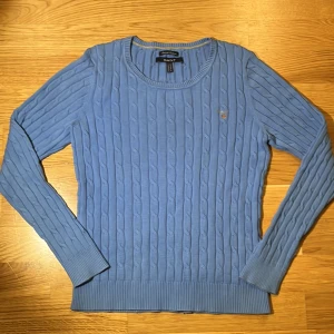 Blå stickad tröja från GANT - Säljer en snygg blå stickad tröja från GANT med kabelstickat mönster. Tröjan har långa ärmar och en rund halsringning. Perfekt för kyligare dagar. 💙 pris inte hugget i sten. Tjejtröja.