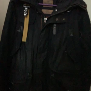 Mörkblå jacka från Parajumpers - Säljer en mörkblå jacka från Parajumpers med dragkedja och knappar. Jackan har en huva och flera praktiska fickor. Perfekt för kyligare väder. Vid snabb affär går priset att diskutera den är även lite sliten på andra armen men då de bara går att lägga upp 5 bilder kunde jag inte få med det. Välkommen att skriva och be om bild på även den slitningen också.