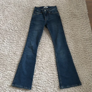 Blå bootcut jeans från Gina tricot - Snygga blå lågmidjade bootcut jeans från Gina tricot. De har en klassisk femficksdesign och stängs med knapp och dragkedja.  Aldrig använda.