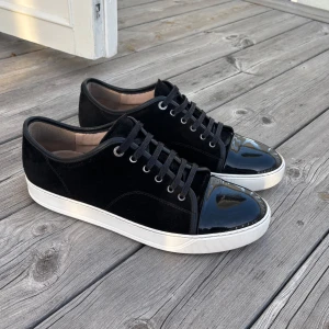 Lanvin uk 9 passar 43/44 - Snygga svarta sneakers från Lanvin med en stilren design. Skorna har en glansig lackad tå och snörning framtill. Perfekta för dig som vill ha en mix av elegans och casual stil. Väldigt bra skick mer bilder kan utdelas vid förfrågan box tillkommer vid köp skorna är i toppen skick utan defekter inga repor eller fläckar, priset kan diskuteras lite grann vid snabb affär.