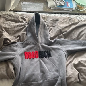 Grå hoodie från Hoodrich - Säljer en grå hoodie från Hoodrich med stor broderad text i rött och svart på framsidan. Tröjan har en klassisk känguruficka och en bekväm huva. Perfekt för en avslappnad stil. Bra fast använd skick. Storleken är junior XL 13-15 år. Säljer den för att den har blivit för liten på mig. Våga lägga prisförslag, priset kan diskuteras. 