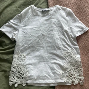 Vit t-shirt med spetsdetaljer från Zara - Vit T-shirt med spetsdetaljer från Zara. Tröjan är i nyskick och endast använd en gång🤍