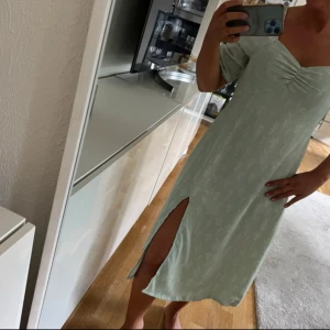 Ljusgrön klänning med slits - Säljer en ljusgrön klänning med ett subtilt mönster och en elegant slits. Klänningen har en v-ringad design och trekvartsärmar, perfekt för vår och sommar. Den är både stilren och bekväm, idealisk för olika tillfällen. Använd en gång 