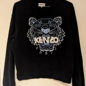 Klassisk Tiger sweatshirt från Kenzo - Mörkblå tröja/sweatshirt från Kenzo, med den klassiska Kenzo Tigern broderad på framsidan.  Tröjan är i mycket fint skick, använd ett fåtal gånger och har inga märken eller skador.  Köpt på NK herravdelning men skulle säga att den är unisex. Kvitto finns.  Upplever att den är lite liten i storleken  Hämtas I centrala Göteborg eller skickas mot frakt.