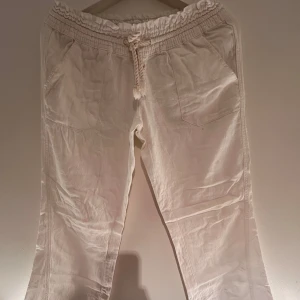 Vita byxor från Roxy - Snygga vita byxor från Roxy med elastisk midja och snörning. Byxorna har en avslappnad passform och är perfekta för en bekväm stil. De har praktiska fickor både fram och bak samt en diskret broderad logga. Dom är uppsydda i benen. Kontakta mig om det är något. Köparen står för köpet💗