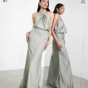 Salviagrön halterklänning - En grågrön långklänning i satin med halterneck. Aldrig använde och säljes pågrund av passerat returdatum. Nypris 1569kr säljes för 1100kr 