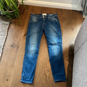 Replay Anbass - Snygga Replay Anbass jeans med klassisk femficksdesign och ljusa tvättade detaljer. Byxorna har en dragkedja och knapp framtill samt dekorativa sömmar på bakfickorna. Liten skada på högra benet…