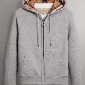 Grå burberry zip hoodie  - Säljer en stilren grå hoodie från Burberry med dragkedja och en klassisk mönstrad huva i beige, rött och svart. Perfekt för en avslappnad look. Den har fickor framtill och justerbara snören vid huvan.Finns i alla storlekar och finns i svart också,        Leveransen kan ta 10-30 dagar.Men värt att vänta för kvalitet och priset 