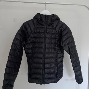 Svart dunjacka från McKinley - Säljer en svart dunjacka från McKinley i storlek 36. Jackan har en quiltad design med dragkedja och huva. Perfekt för kyliga dagar och håller dig varm och bekväm. En stilren och praktisk jacka för alla tillfällen.