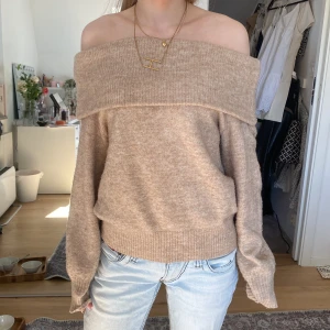 Beige offshoulder tröja - Säljer en mysig beige offshoulder tröja med långa ärmar. Tröjan har en ribbad kant upptill och vid ärmsluten, vilket ger en stilren look. Perfekt för en avslappnad stil.