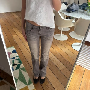 Grå jeansbyxor  - Snygga grå jeansbyxor med en bootcut-stil. Byxorna har en lågmidjad passform och klassisk femficksdesign. Perfekta för en avslappnad look. W 28 L 31