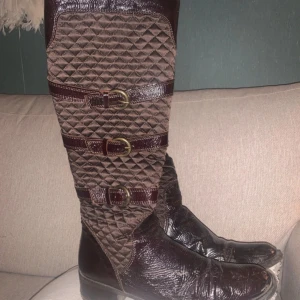 Bruna quiltade stövlar med spännen - Snygga bruna stövlar med quiltat mönster och flera dekorativa spännen. Stövlarna har en dragkedja på sidan för enkel på- och avtagning. 