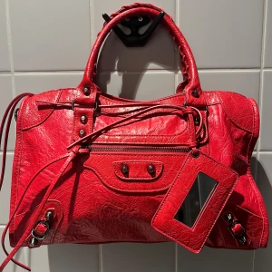 City bag - Ruby - (OBS! inte begagnad! Finns även att beställa via vår hemsida www.ivysthlm.se) CITY BAG – Den perfekta statment väskan som livar upp varje vardags-outfit. Lika praktisk som snygg och fungerar både till skola & fest – Ja, din dator får plats! (väskan levereras med ett långt, justerbart axelband för extra bekvämlighet) Storlek: 38×10×23 cm Finns även tillgänglig i grå och svart! Äkta läder