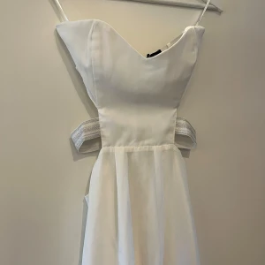 Vit klänning med glittriga detaljer - Super fin vit klänning med cut out i ryggen och sidorna, perfekt till sommarens fester! Den är från Nelly (köpt typ 2014) och använd 1 gång. Är storlek S och de glittriga banden är stretchiga. 