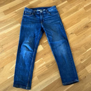 Blå jeans från H&M - Säljer ett par blå jeans från H&M med relaxed fit och justerbar midja. Byxorna har en tapered leg design och klassisk femficksmodell. Är inte baggy men sitter inte heller tajt. Storleken passar för de som är från 160 till 175 centimeter långa
