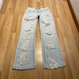 Lågmidjade bootcut jeans med slitningar - (14) De perfekta ljusblåa lågmidjade jeansen i stretchigt material med massa snygga slitningar och specialfickor! Midjemått rakt över: 33 cm, innerbenslängd: 71 cm 💙