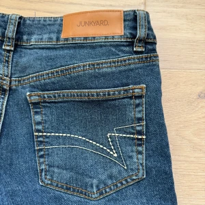 Blå jeans från Junkyard - Säjer mina trendiga blåa jeans från Junkyard. Jeansen är lågmidjade, bootcut med en fin detalj på bakfickorna. Helt nya bara testade en gång.