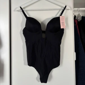 Svart body från H&M - Snygg svart body från H&M med justerbara axelband och vadderade kupor