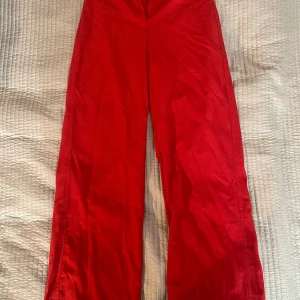 Röda kostymbyxor från Bershka - Snygga röda byxor från Bershka med en vid passform. Perfekta för att sticka ut med en djärv färg. Tillverkade i ett bekvämt material som ger en skön känsla hela dagen.