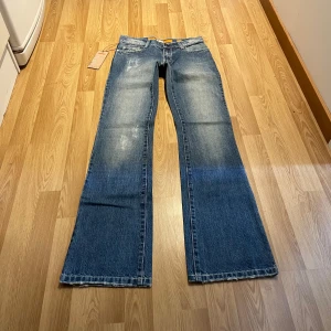 Lågmidjade bootcut jeans med strass - (15) Snygga lågmidjade jeans, helt nya med lappar kvar! Stretchigt material och i storlek 26, så unika detaljer på! Midjemått rakt över: 36 cm, innerbenslängd: 85 cm 💖