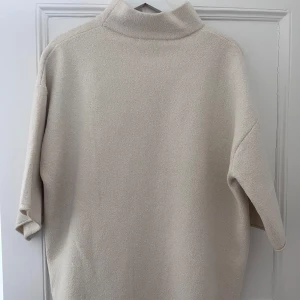 Beige tröja från Zara - Säljer en beige tröja från Zara med en hög krage och trekvartsärmar. Tröjan är tillverkad i ett mjukt material som ger en bekväm passform.