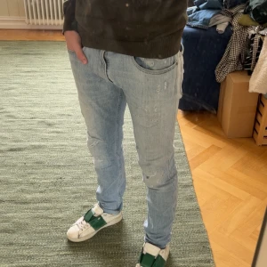 Ljusblå Replay Anbass med slitningar - Säljer ett par ljusblå Anbass från Replay med coola slitningar. De har en klassisk femficksdesign och en läderpatch med logga på baksidan. Perfekta för en avslappnad stil