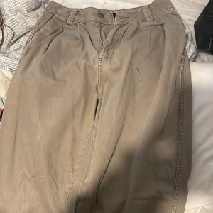 Beige byxor från Bershka - Snygga beige byxor från Bershka med normal passform. Byxorna har en klassisk design med knappar och dragkedja framtill. Perfekta för en stilren look.