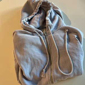 Ljusblå hoodie från Brandy Melville - Mysig ljusblå hoodie från Brandy Melville med dragkedja framtill, huva med snörning och känguruficka. Tillverkad i mjuk bomullsmix, perfekt för chill dagar. Klassisk passform och långa ärmar.