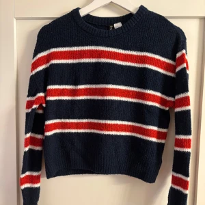 Randig stickad tröja  - Mysig stickad tröja från H&M i marinblått med röda och vita ränder. 