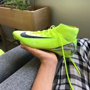 Nike Mercurial fotbollsskor neongula - Säljer ett par Nike Mercurial fotbollsskor i en riktigt skarp neongul färg med svarta detaljer och Nike-logga. Skorna har snörning, högre strumpliknande skaft och är tillverkade i syntetmaterial med NIKESKIN för extra känsla på planen.