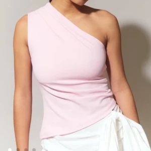 Ljusrosa oneshoulder topp - Snygg ljusrosa topp med oneshoulder-design och figurnära passform. Perfekt för dig som vill sticka ut med en enkel men trendig look. Mjuk och stretchig känsla, passar till både jeans och kjol.