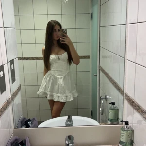 Vit kort klänning med volang - Superfin vit klänning från Urban outfitters. Knytning baktill och en diskret dragkedja på sidan. Använd 1 gång och passar xs-s 💕tar mer än gärna prisförslag 