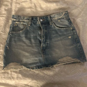 Blå jeanskjol från Pull&Bear - Snygg ljusblå jeanskjol från Pull&Bear med slitna detaljer. Kjolen är jättefin och är perfekt nu till sommaren. Använts minst 3 gånger!!