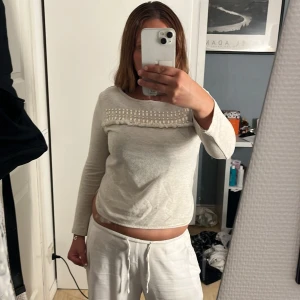 Beige långärmad tröja med pärlor H&M - Supersöt beige långärmad tröja från H&M med unika pärldetaljer och fransar över bröstet. Tröjan har rund halsringning och är i mjuk bomullsmix, perfekt för dig som gillar detaljer som sticker ut. Saknar en pärla men inget man tänker på💕