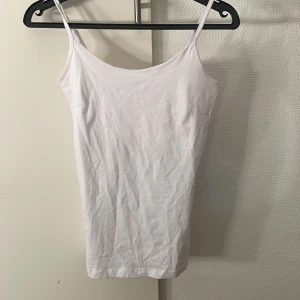 Vit linnetopp från Basic You XS - Säljer en enkel och stilren vit linnetopp från Basic You i storlek XS. Toppen har smala axelband och är gjord av mjuk ekologisk bomull, perfekt för varma dagar eller som lager under andra plagg.
