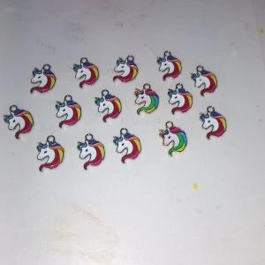 Färgglada enhörningsberlocker - Säljer flera små enhörningsberlocker i metall med vit bas och regnbågsfärgad man. Perfekta att använda till armband, halsband eller örhängen. Berlockerna har detaljer i blått, rött, gult, grönt och lila samt en glittrig horn-detalj.