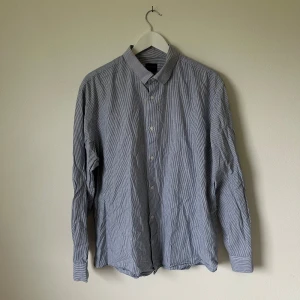 Randig skjorta från Selected Homme - Snygg randig skjorta från Selected Homme i blått och vitt. Slim fit-modell med klassisk krage och knäppning framtill. Tillverkad i en skön mix av bomull och linne, perfekt för en fräsch och stilren look. Långärmad och passar dig som gillar en smalare passform. Artnr: C372