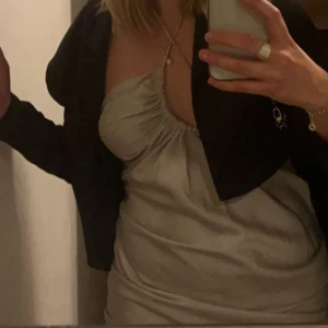  Festklänning - Supersnygg beige kort klänning med rynkade detaljer och cut out i midjan. Klänningen har halterneck med knyt i nacken och knappar bak🌙