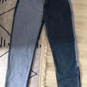 Tvåfärgade raka jeans i blått och grått - Unika jeans med tvåfärgad design – ena benet är ljusgrått och det andra mörkblått. Raka ben och klassisk femficksmodell. Jeansen har cool kontrast mellan färgerna både fram och bak. Perfekta för dig som vill sticka ut med din stil.