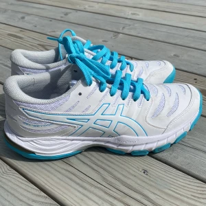 Vita och turkosa Asics sneakers - Snygga Asics Gel-Beyond sneakers i vitt med turkosa detaljer och snörning. Ovandelen är i mesh och syntet för bra andningsförmåga. Sulan har dämpning med FlyteFoam-teknologi och skon har en sportig, modern look. Perfekta för dig som gillar stilrena träningsskor.