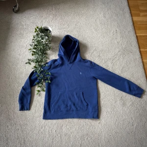 Blå Ralph Lauren hoodie storlek large  - Äkta Ralph Lauren hoodie i klassisk blå färg. Storlek: L (passar som svensk large) Material: 84% bomull, 16% polyester – mjuk och bekväm. Tröjan är i mycket bra skick, knappt använd. Inga fläckar, noppor eller hål.  📦 Skickas snabbt & säkert. Fråga gärna om du undrar något!